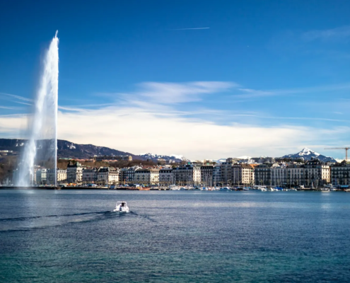 Le Jet d’eau et la rade de Genève sous un ciel bleu, avec les montagnes en arrière-plan